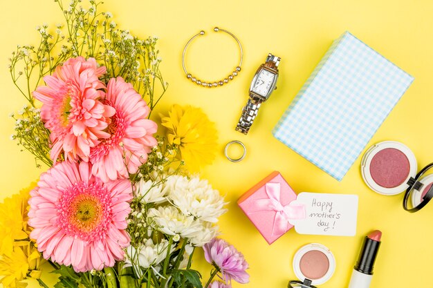 Manojo de flores frescas cerca de la etiqueta con palabras del día de la madre feliz en la caja actual y accesorios