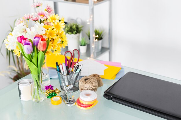 Manojo de flores frescas con papelería en el escritorio