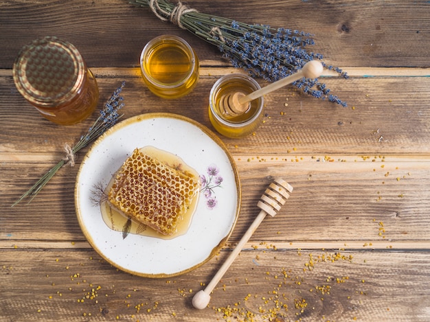 Manojo de lavanda; tarro de miel; y pieza de panal en el plato sobre la mesa