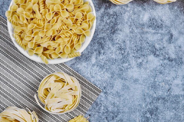 Un manojo de pasta cruda sobre mármol.