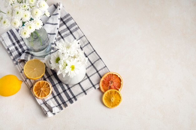 Manojos de flores frescas en florero y jarra cerca de frutas en servilleta