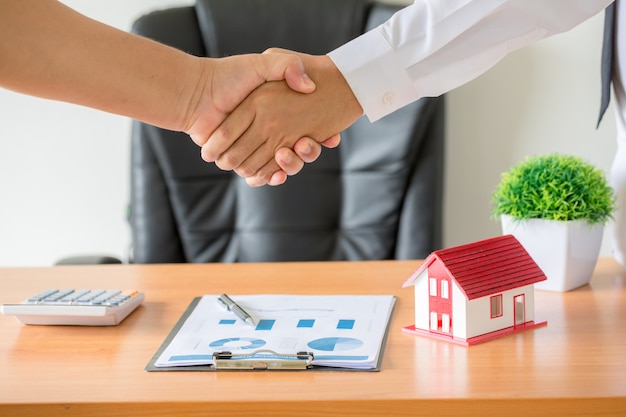 manos del agente y del cliente estrechándose la mano después de firmar un contrato, comprar un apartamento nuevo