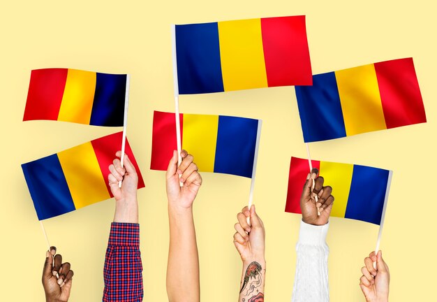 Manos agitando banderas de rumania