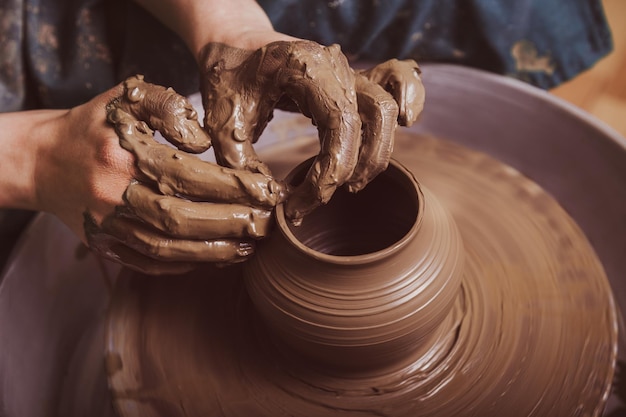Manos de un alfarero, creando una vasija de barro