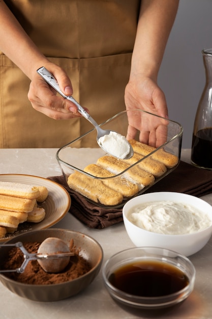 Manos de alto ángulo cocinando delicioso tiramisú