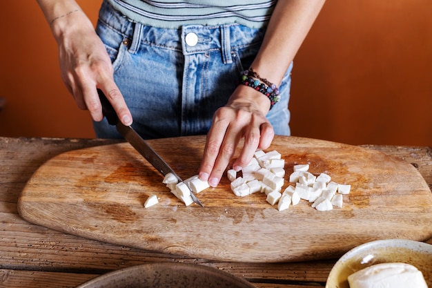 Manos de alto ángulo cortando queso