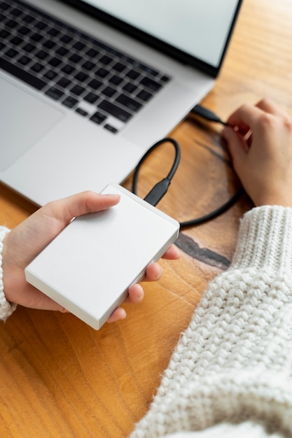 Manos de alto ángulo que conectan ssd a la computadora portátil
