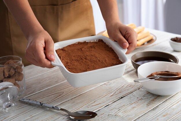 Manos de alto ángulo sosteniendo bandeja de tiramisú