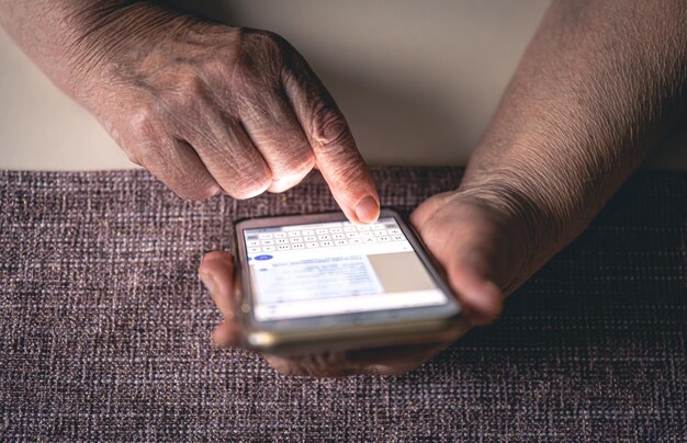 Manos de una anciana sosteniendo un teléfono móvil