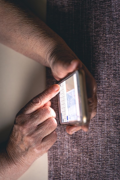 Manos de una anciana sosteniendo un teléfono móvil