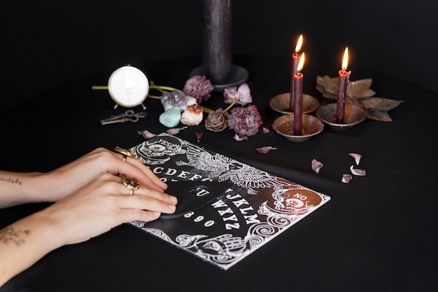 Foto gratuita manos de ángulo alto usando tablero de ouija