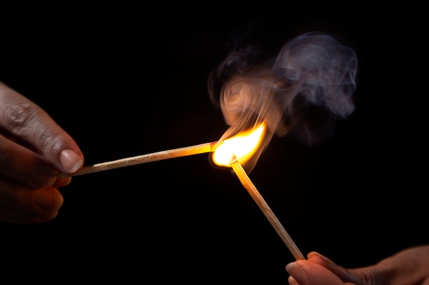 Manos de ángulo bajo sosteniendo fósforos encendidos