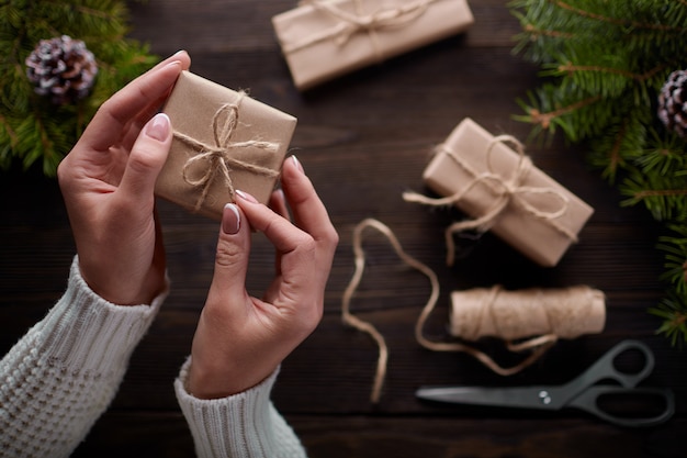 Manos atando el nudo de cordel de paquetes de regalo