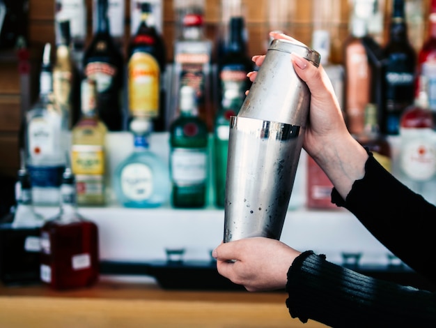 Las manos del barkeeper de la cosecha que preparan la bebida en coctelera