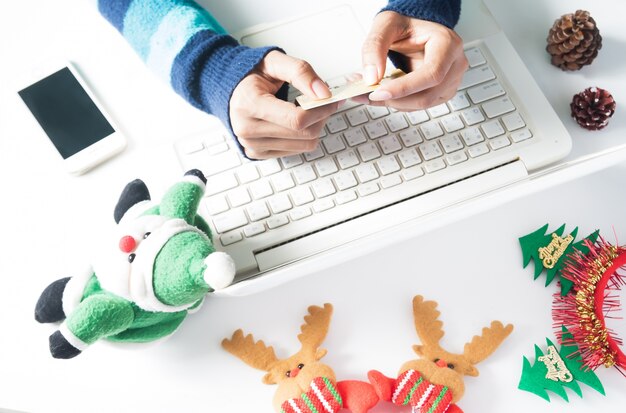 Manos celebración de tarjeta de crédito y el uso de portátil, smartphone con la decoración de Navidad, Compras en línea