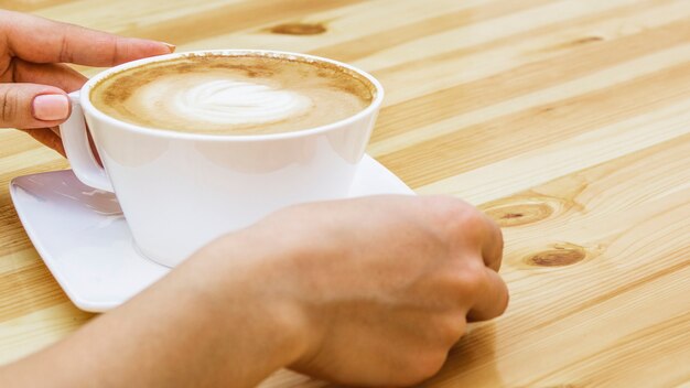 Manos cogiendo taza de café