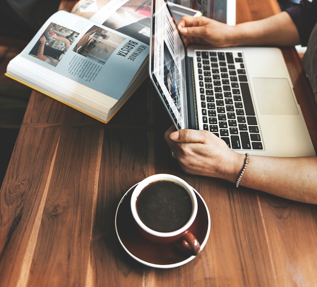 Foto gratuita manos con la computadora portátil en la mesa de madera en café café