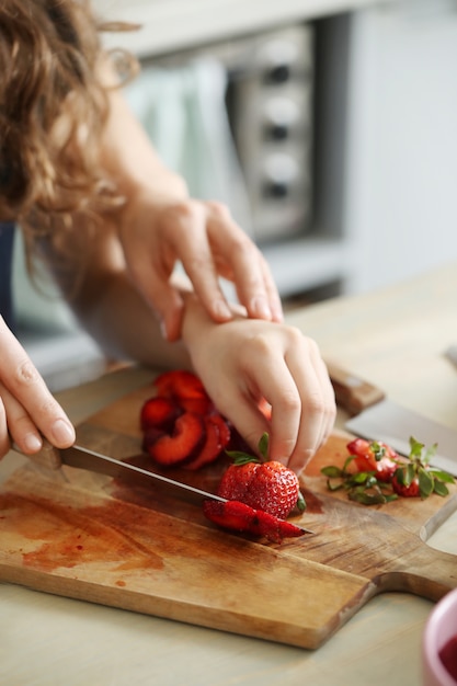 Manos cortando fresas frescas