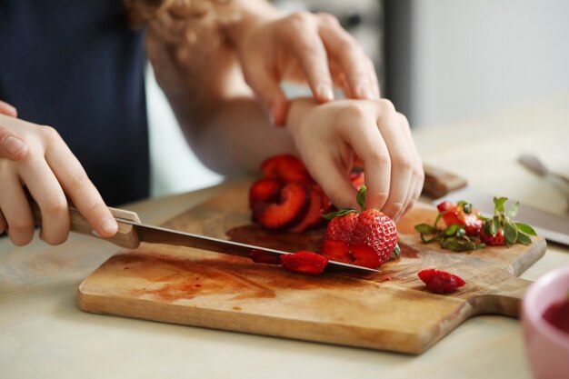 Manos cortando fresas frescas