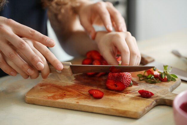 Manos cortando fresas frescas