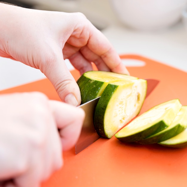 Foto gratuita manos cortando pepino