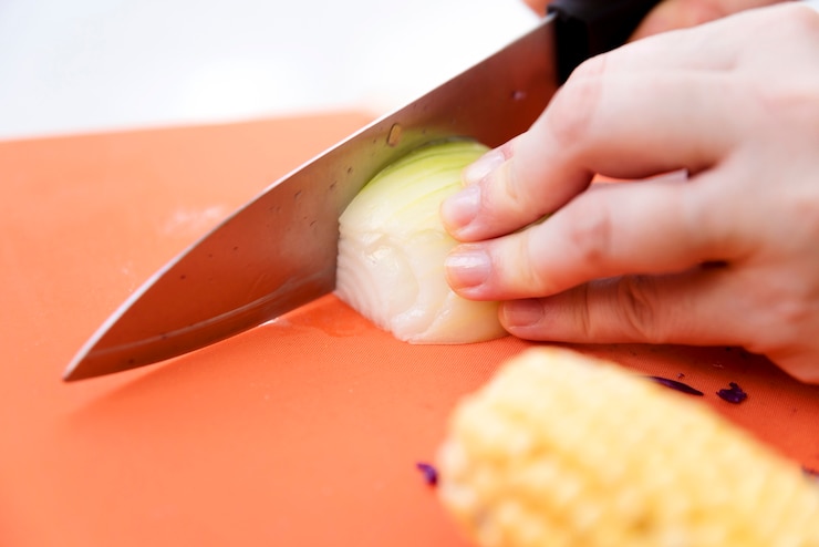 Foto gratuito manos cortando pepino