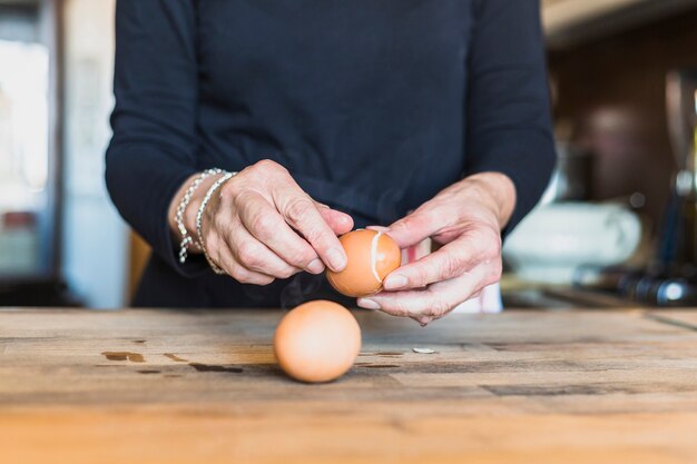 Las manos de la cosecha de la mujer mayor que cocina en cocina