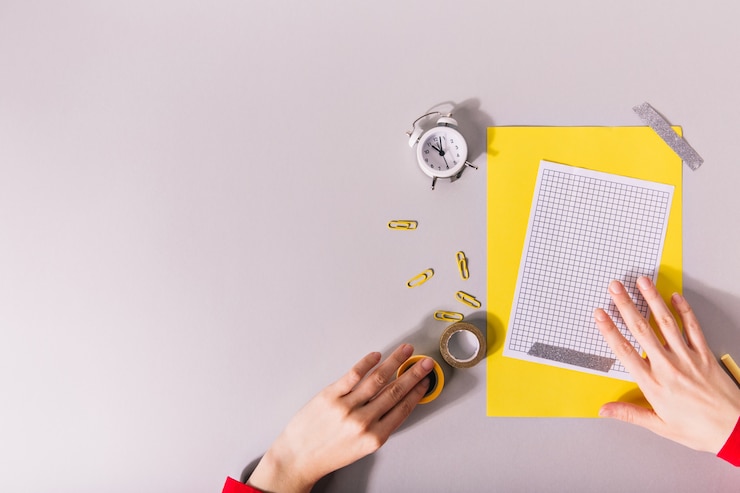 Foto gratuito manos creando composición de papel amarillo y clips brillantes