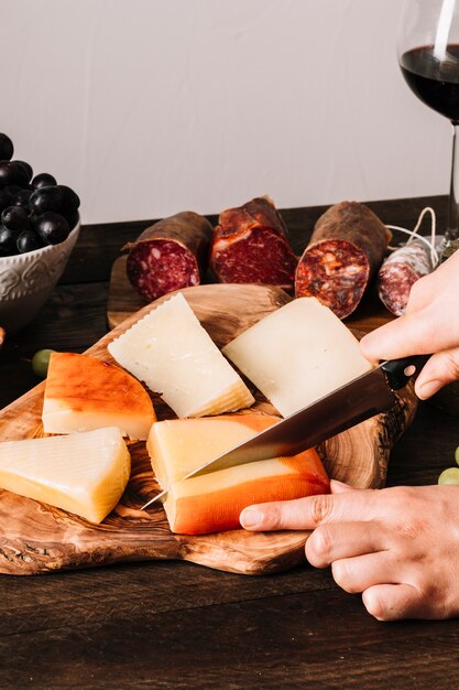 Manos de cultivo cortando queso