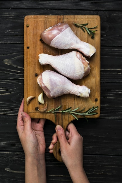 Manos de cultivo sosteniendo la tabla con patas de pollo