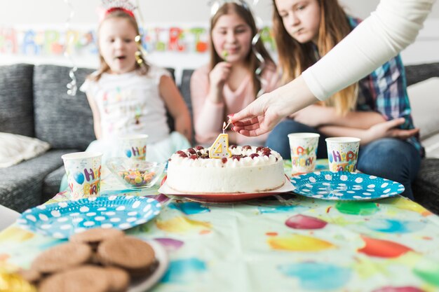 Manos de cultivos encendiendo velas en el pastel