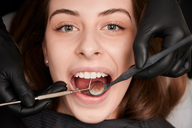 Foto gratuita manos de dentista en guantes estériles examinando dientes de mujer