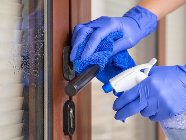 Manos desinfectando la manija de la puerta con ablución y tela