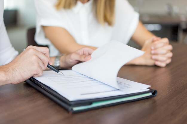 Manos del ejecutivo de sexo masculino que muestran el contrato a la socio femenina en la reunión.