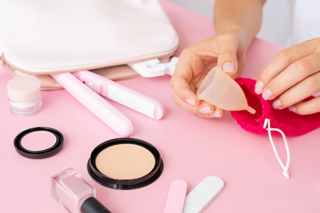 Manos empacando copa menstrual alto ángulo