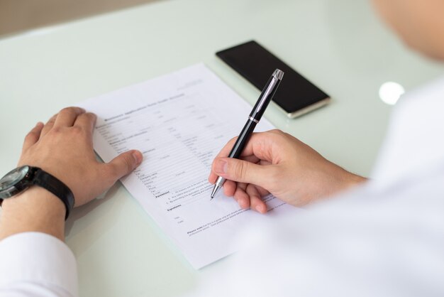 Manos del empresario o estudiante rellenando el formulario de solicitud.