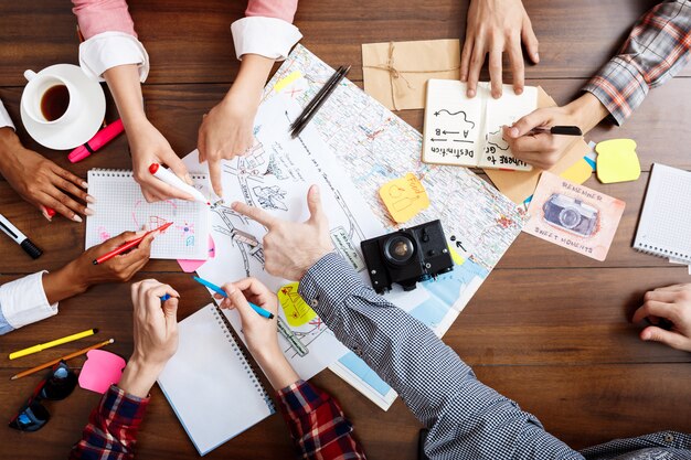 manos de empresarios en mesa de madera con documentos y borradores