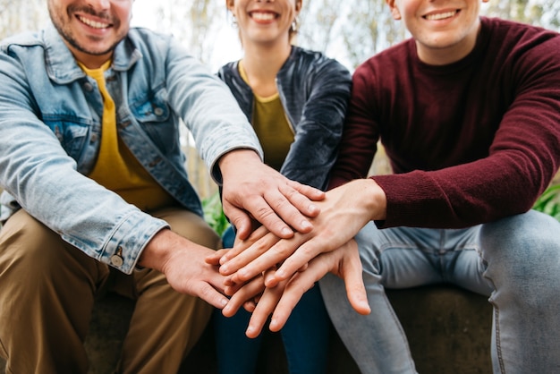 Foto gratuita manos encima de la otra de amigos sonrientes en el fondo