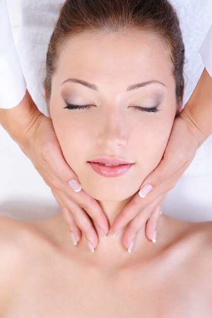 Manos de esteticista dando masaje facial de mujer bonita