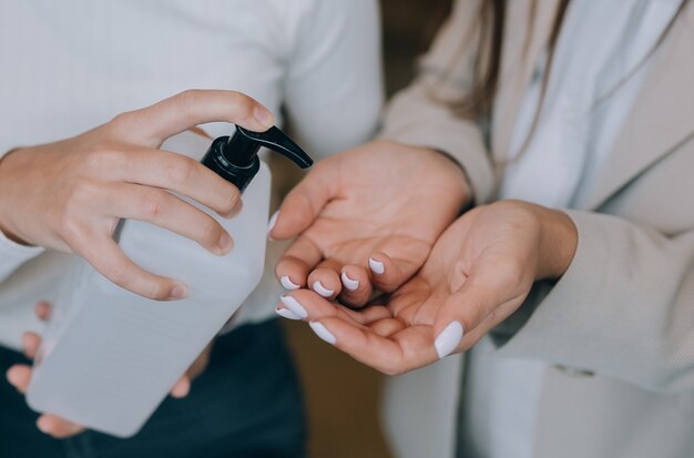 Manos femeninas aplicando jabón líquido antibacteriano de cerca.