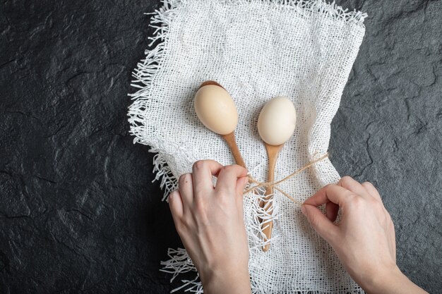 Manos femeninas ata arpillera con huevos