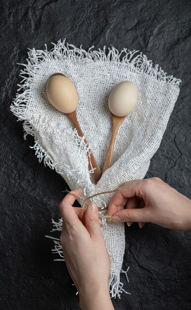 Manos femeninas ata arpillera con huevos