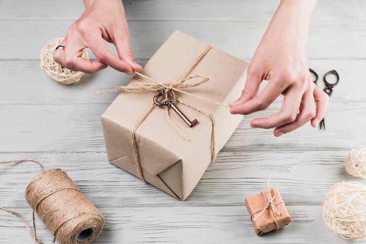 Foto gratuito las manos femeninas atan la cadena en el regalo envuelto en el escritorio de madera