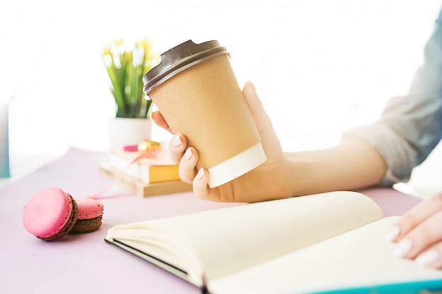 manos femeninas con café. Escritorio rosa de moda.