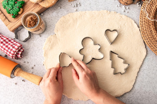 Foto gratuita las manos femeninas cortan formas y hacen galletas de navidad.