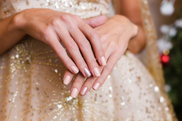 Manos femeninas con diseño de uñas de año nuevo de Navidad. Manicura de esmalte de uñas beige nude