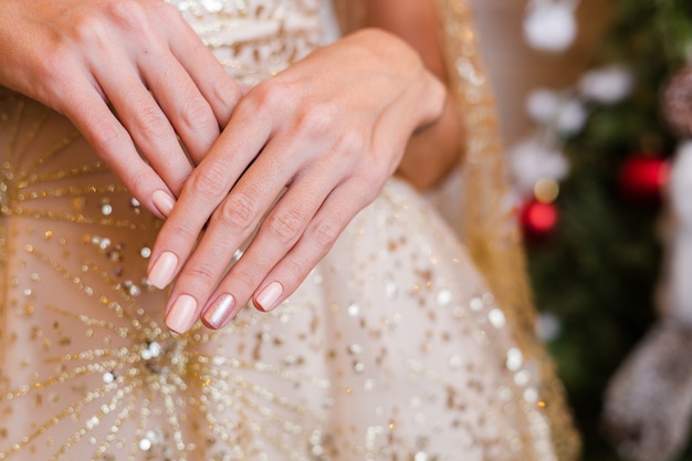 Manos femeninas con diseño de uñas de año nuevo de Navidad. Manicura de esmalte de uñas beige nude