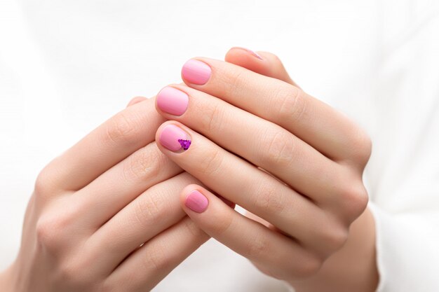 Manos femeninas con diseño de uñas de color rosa.