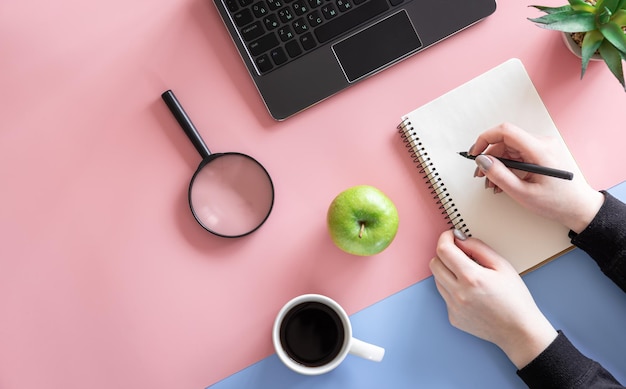 Las manos femeninas están escribiendo en un cuaderno plano y minimalista conceptual.