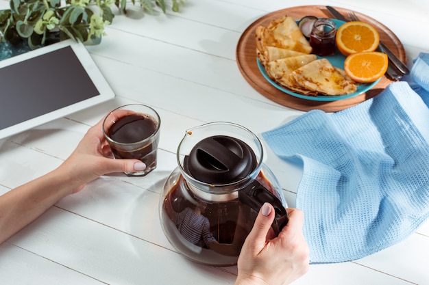 manos femeninas y panqueques con jugo. Desayuno saludable